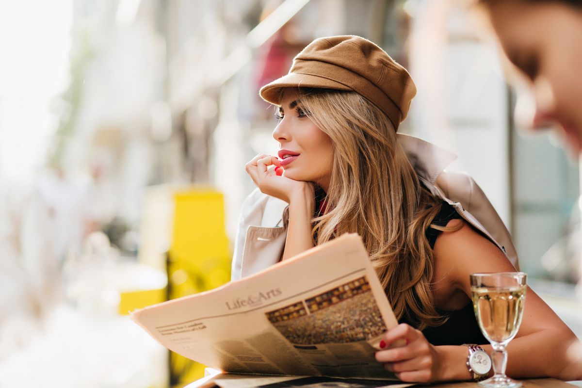 dreamy-woman-brown-cap-thinking-about-something-propping-face-with-hand-holding-newspaper-outdoor-portrait-amazing-blonde-girl-with-glass-wine-posing-blur-city-background_result_result