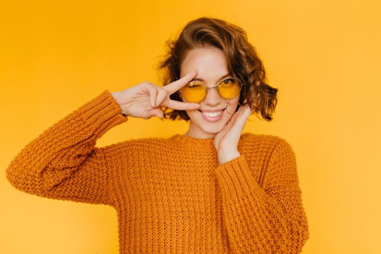 joyful-european-woman-with-shiny-curls-laughing-showing-peace-sign-yellow-background