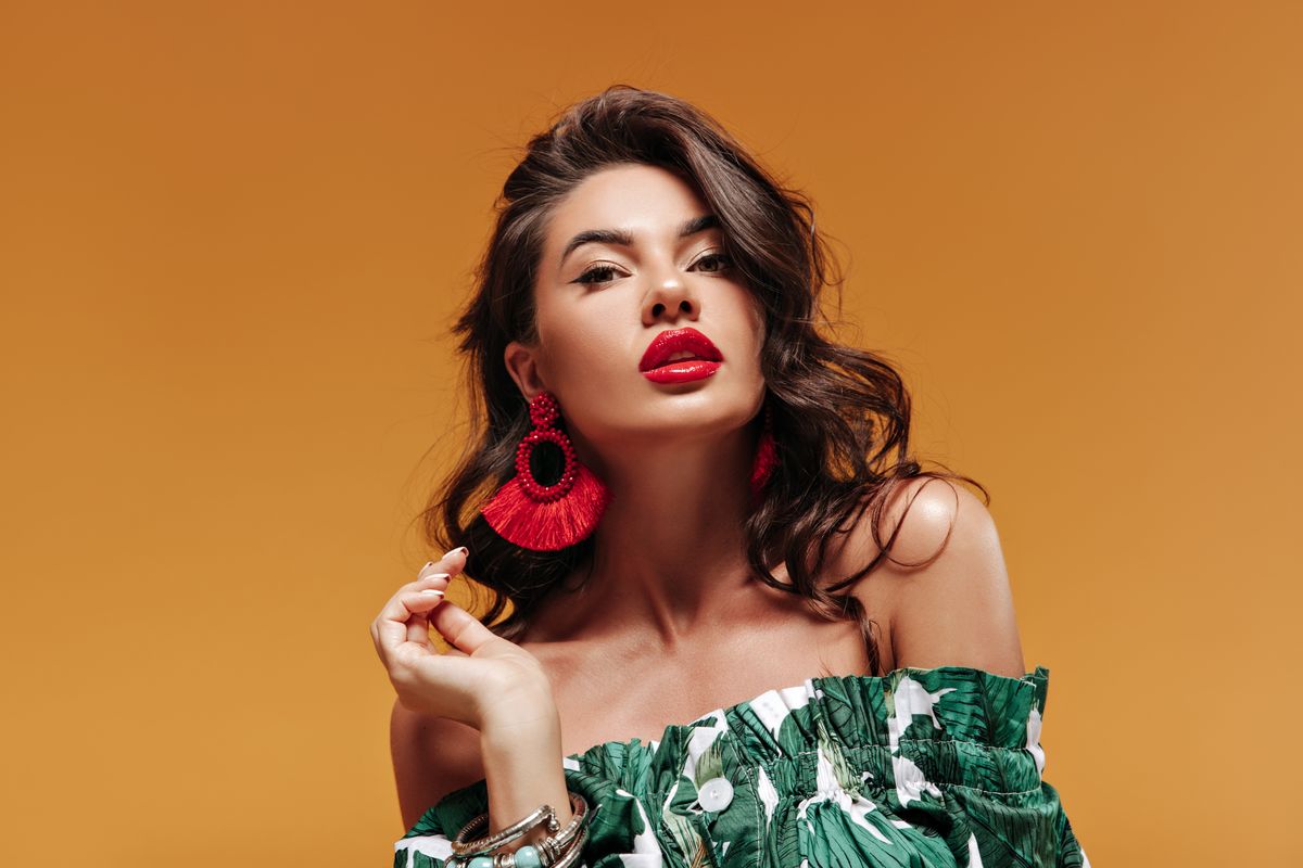 trendy-attractive-woman-with-wavy-hairstyle-with-modern-cool-earrings-big-red-lips-green-sundress-looking-into-camera_result